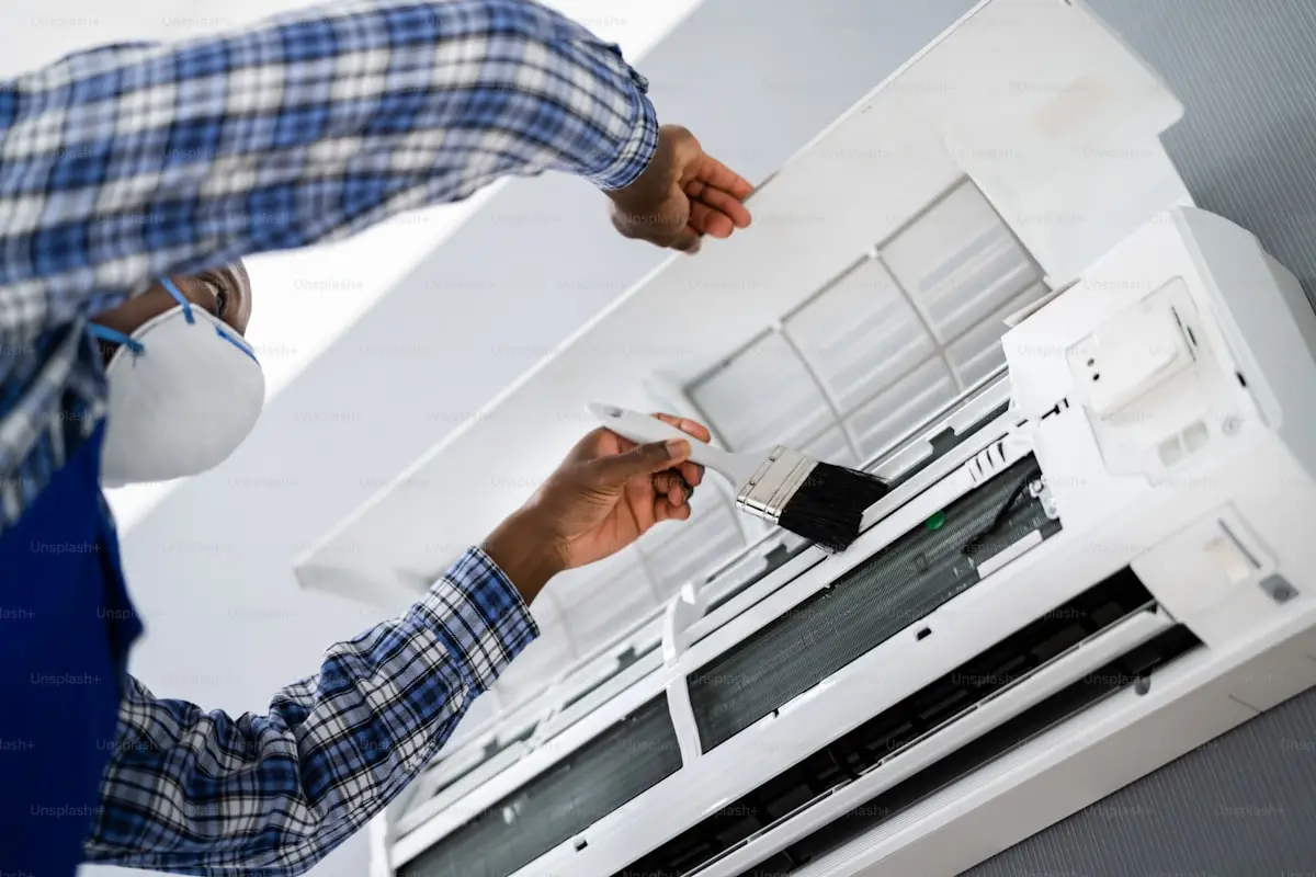 Technician performing a complete split-type air conditioner cleaning, including filter, evaporator coil, and drainage maintenance